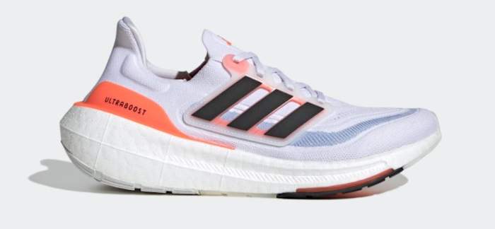 Side view of a white and orange adidas shoe.